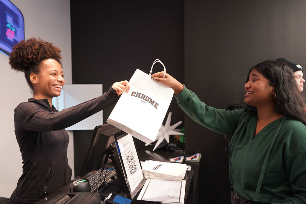 Cashier at Chrome Flwrs dispensary giving a happy customer her order at the checkout counter